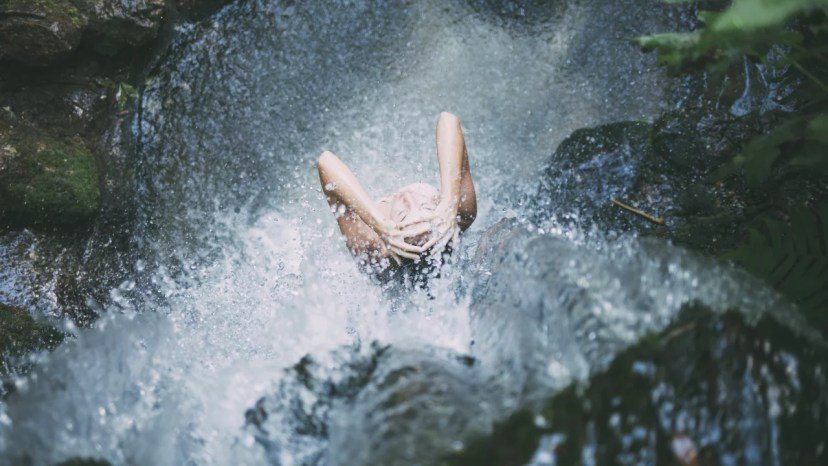 Femme sous une cascade d'eau fraiche